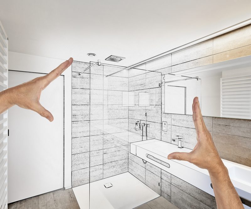 A pair of hands measures a bathroom layout designed by Bath Crest Home Solutions
