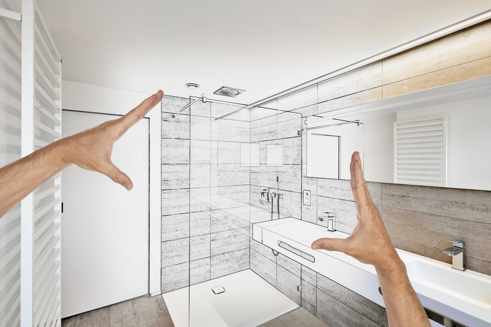 A pair of hands measures a bathroom layout designed by Bath Crest Home Solutions