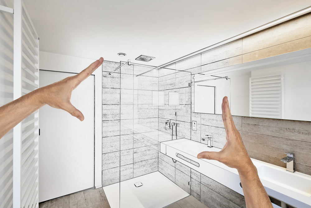 A pair of hands measures a bathroom layout designed by Bath Crest